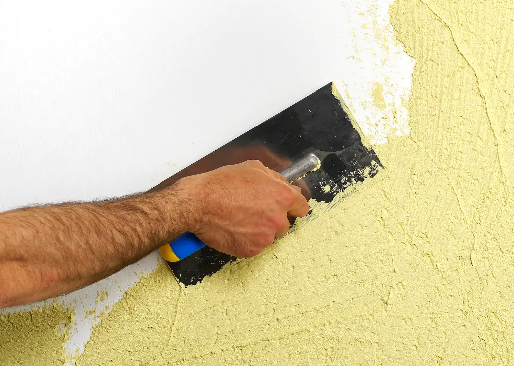 Application d'enduit sur un mur au couteau à enduire, ravalement de façade