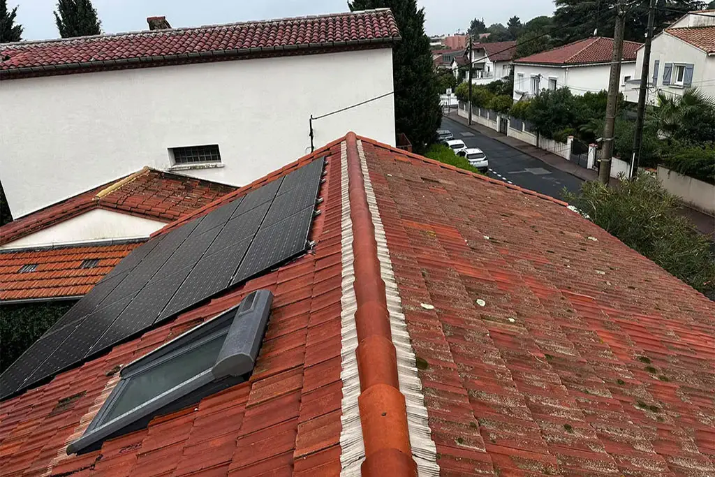 Toiture en tuiles rouges avec panneaux solaires et fenêtre de toit, réparation de toiture à Montpellier